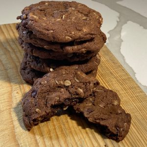 Stack of peanut butter cookies with crisscross fork marks on a wooden board, one cookie leaning against the front
